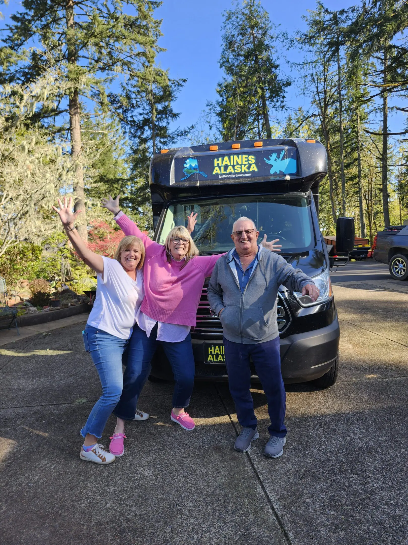 TWO WOMEN AND A MAN INFRONT OF A VAN