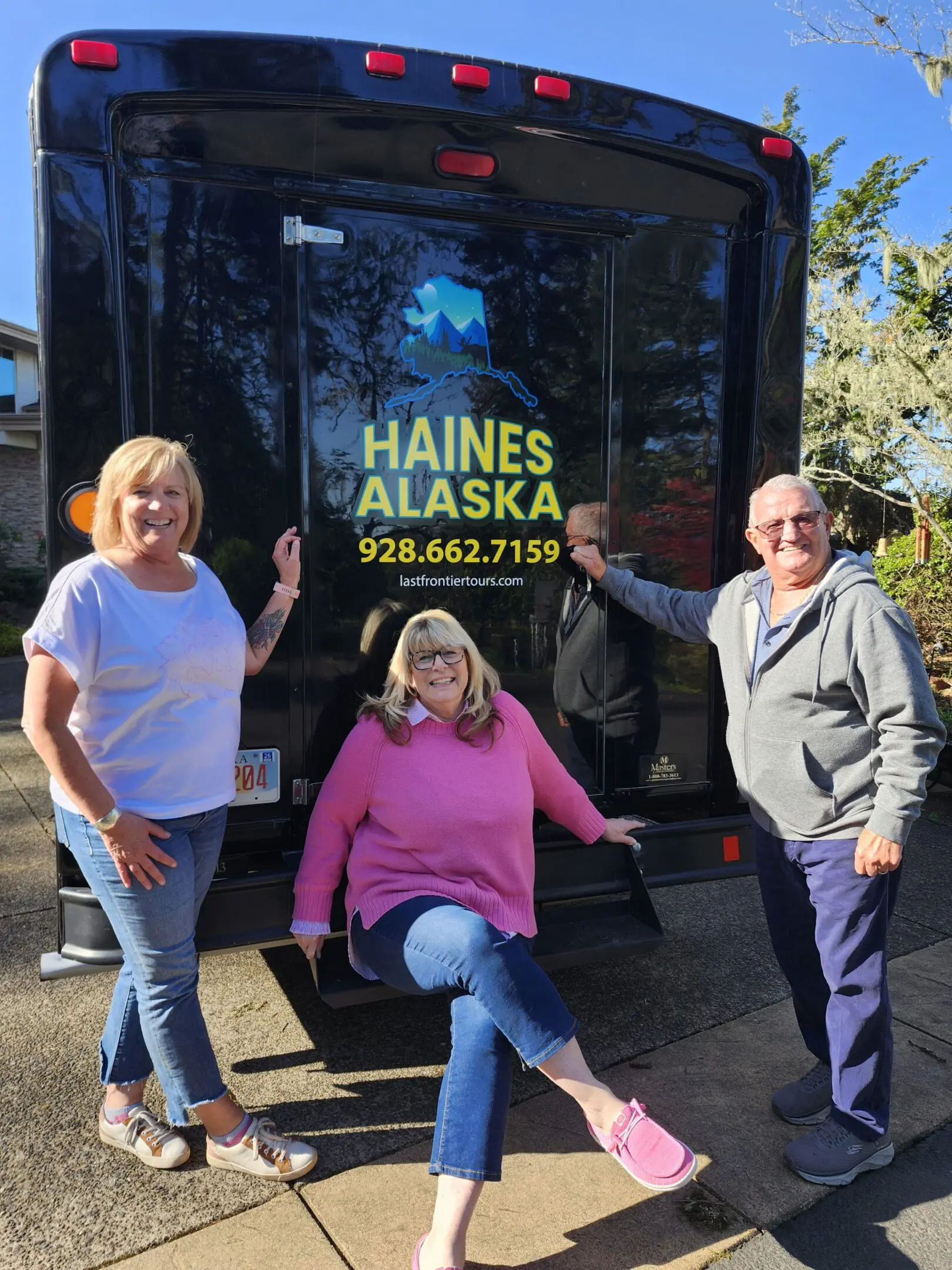 TWO WOMEN AND A mAN NEAR A BUS